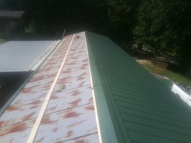 Old rusted panels beside newly installed green metal roofing — Wind Damage Roof Repair by Roofing Brothers in Detroit